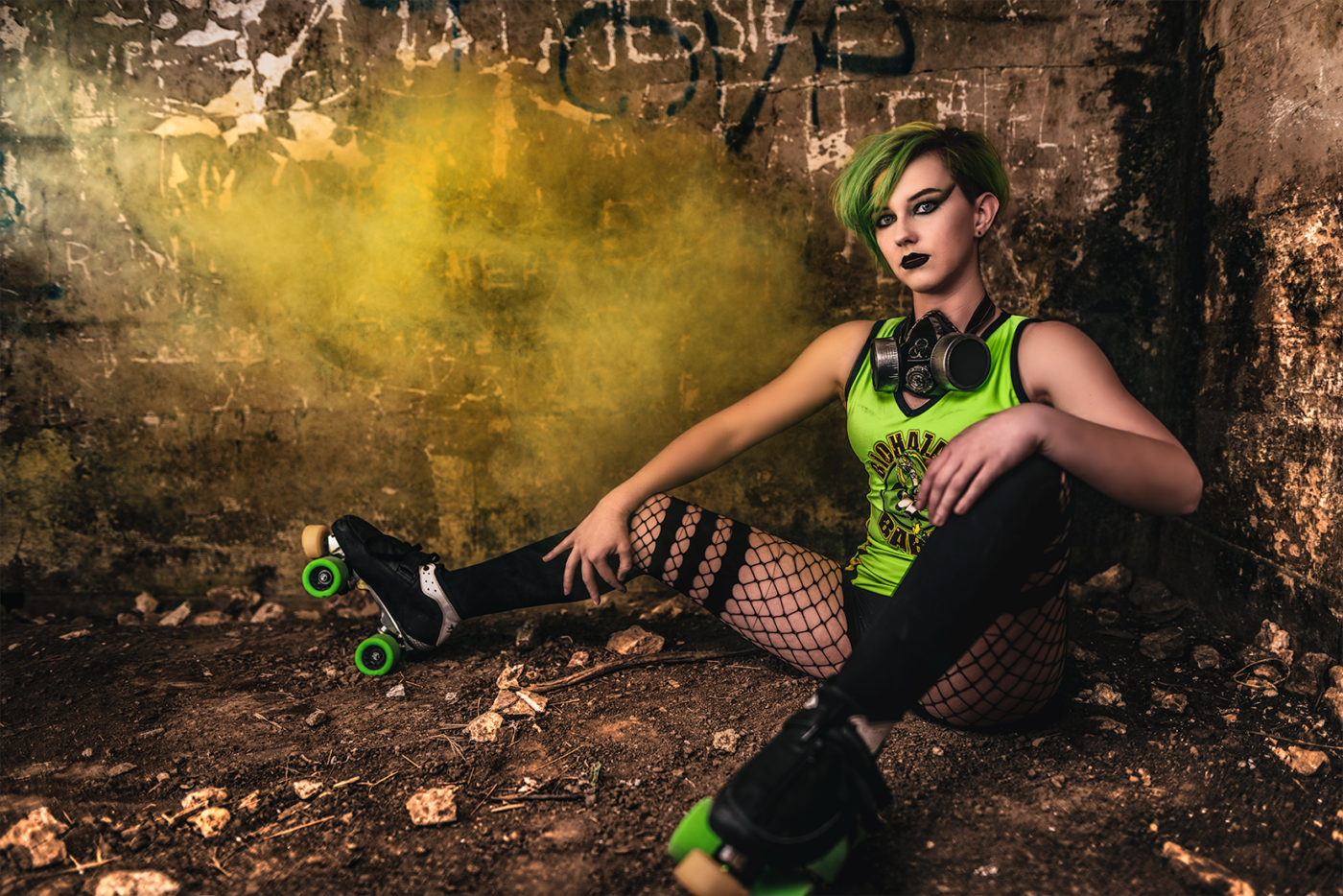 A girl in green roller skates sitting on a dirt floor captured by Houston Photographer, Chris Spicks Photography.