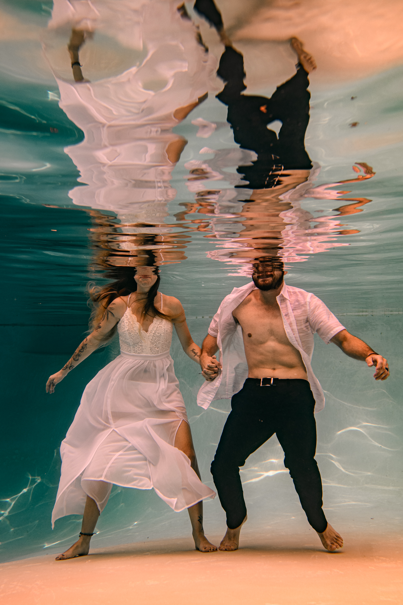 Chris Spicks Photography captures a creative and unique moment in Houston, featuring a bride and groom standing under water in their wedding dress.