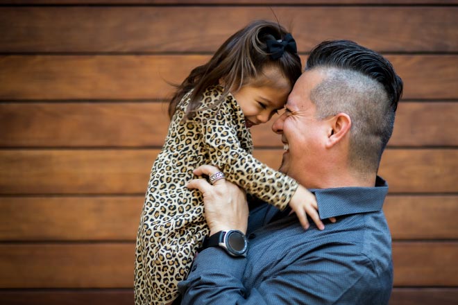 A creative photography captured by Houston photographer, Chris Spicks, featuring a man holding a little girl in front of a wooden wall.